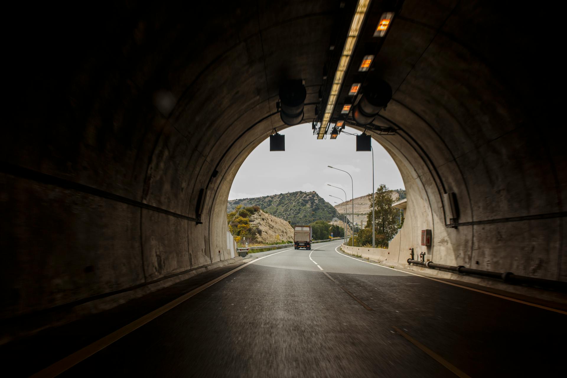 Truck driving through a scenic tunnel on a highway in Cyprus, with mountains in view.