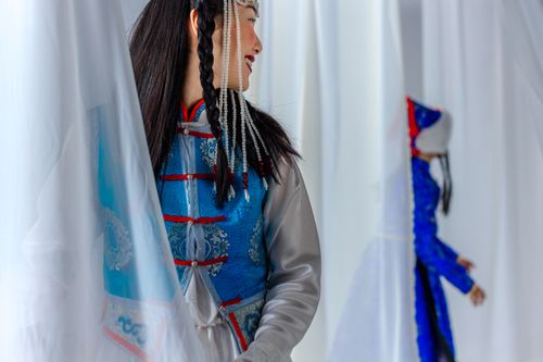 Free Asian woman wearing vibrant hanfu dress, partially hidden by white curtains. Stock Photo