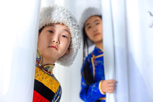 Sisters Hiding behind White Curtains