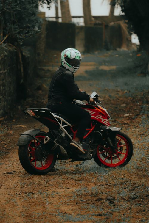 Free A motorcyclist wearing a helmet rides on a dirt road surrounded by nature, showcasing adventure and freedom. Stock Photo