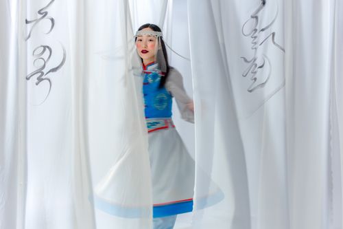 Free Asian woman in traditional clothing partially hidden behind flowing curtains, creating a motion blur effect. Stock Photo