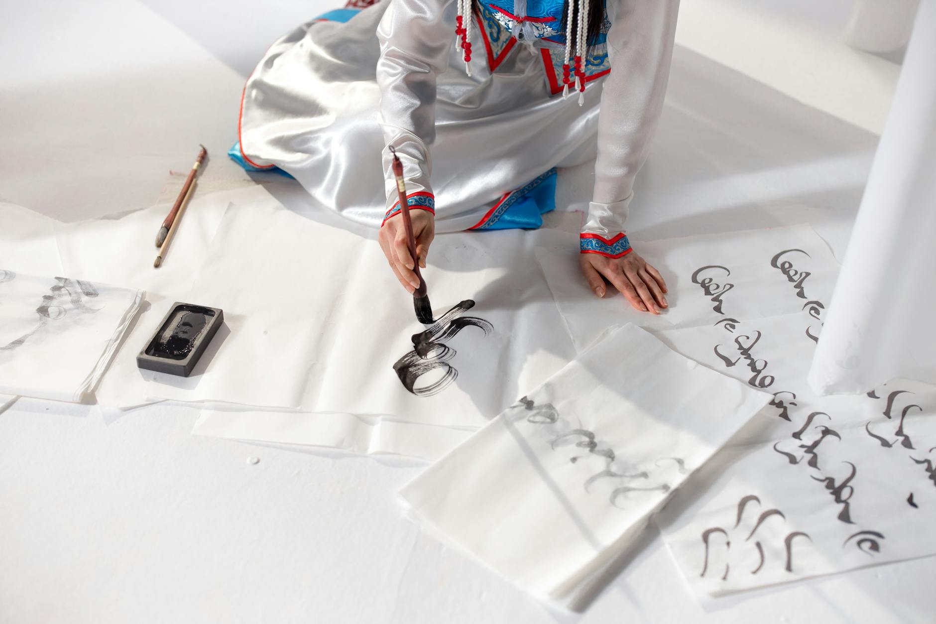 A Person on White Surface Using Brush for Calligraphy