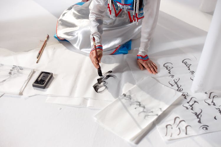 A Person On White Surface Using Brush For Calligraphy