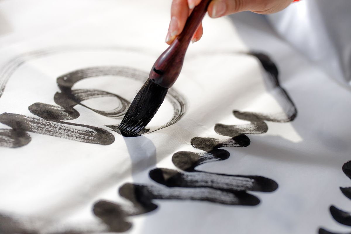 A hand writing calligraphy with a brush and black ink