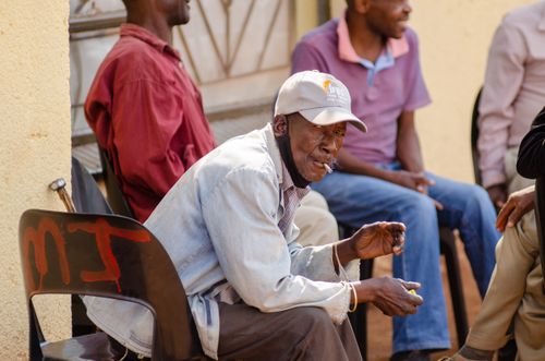Free Group of men sitting and smoking outside on a sunny day, wearing casual clothes. Stock Photo