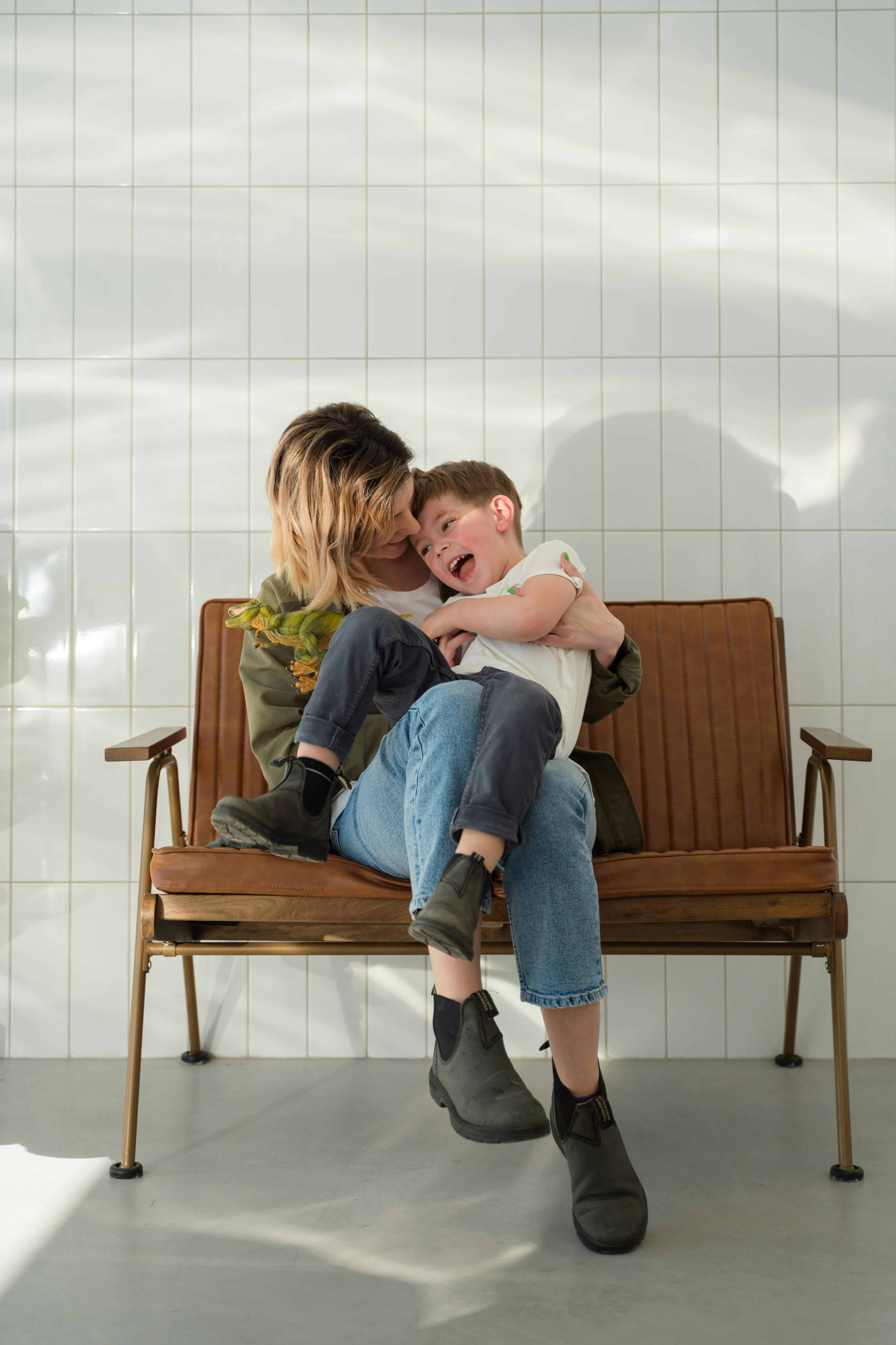 mother and son playing together while sitting on a brow couch