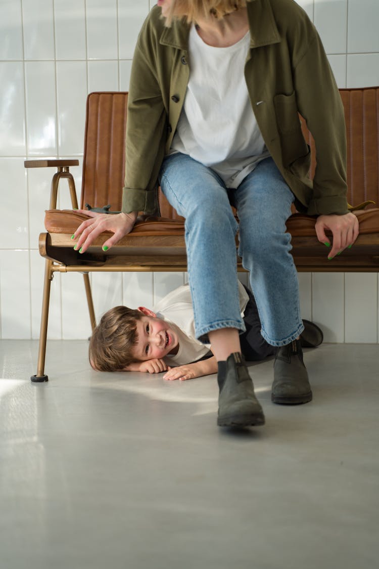 A Cute Little Boy Hiding Under The Couch