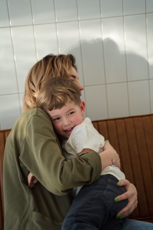 Free A joyful mother and son sharing a warm hug in a sunlit room, capturing a moment of love and bonding. Stock Photo