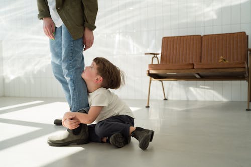 Free Boy Sitting on the Floor while Hugging a Person's Leg Stock Photo