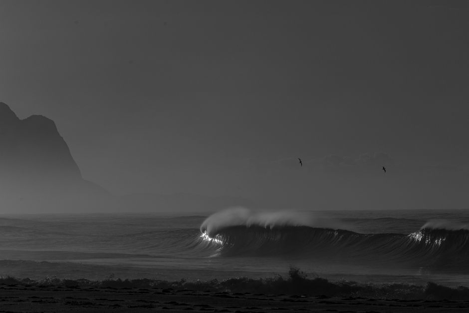 A dramatic grayscale ocean scene with waves and distant hills, enhancing the serene landscape.