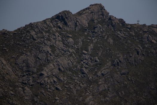 Explore the rugged beauty of a rocky mountain peak under a clear blue sky, showcasing natural formations.