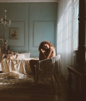 Curly-haired woman sitting in a vintage bedroom, evoking a sense of melancholy and introspection.