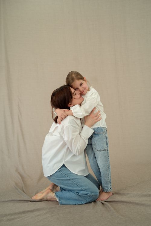 Free A touching moment between a mother and daughter in a studio setting, both wearing casual outfits. Stock Photo