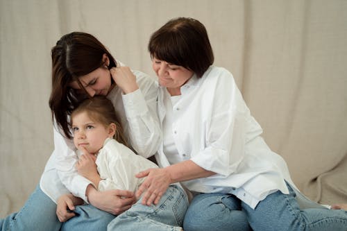 Mother and Daughters in White Shirts Embracing