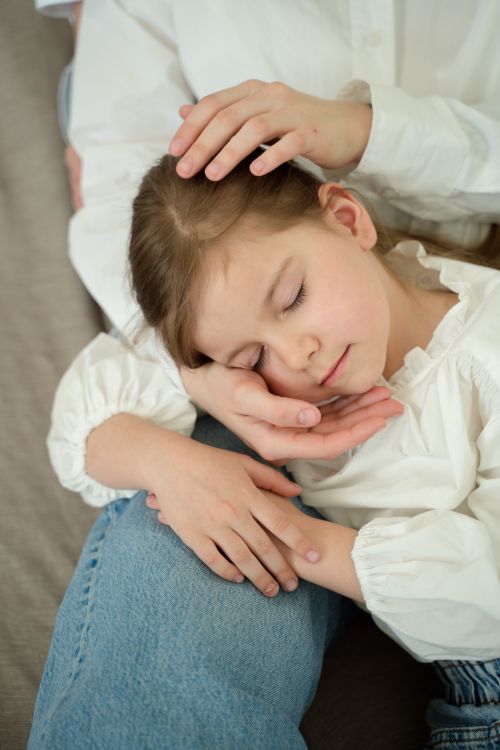 Free A heartwarming scene of a mother gently holding her sleeping daughter, showcasing love and tenderness. Stock Photo