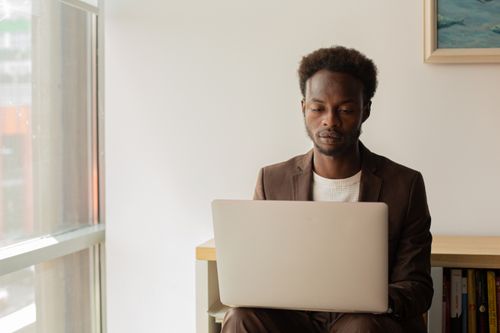 Free An adult professional male working on a laptop in a bright, modern office setting. Stock Photo