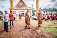 Monks and people gather for a temple ceremony outdoors, showcasing cultural traditions.