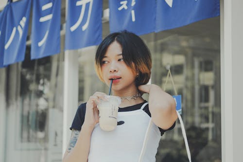 A Woman in Black and White Shirt Holding a Juice in Plastic Cup