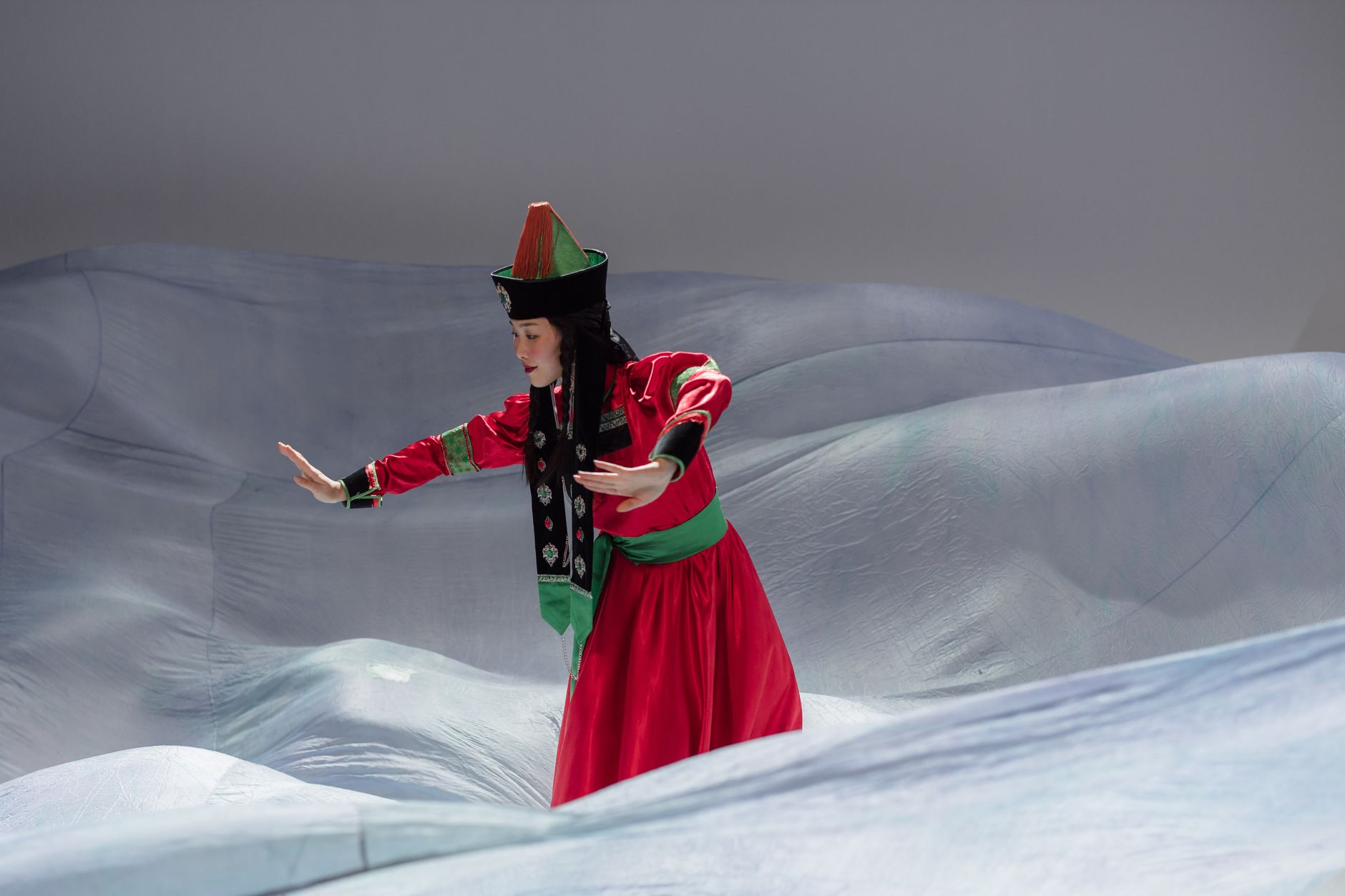 A woman in traditional Mongolian attire performs a dance in a studio environment, showcasing cultural heritage.