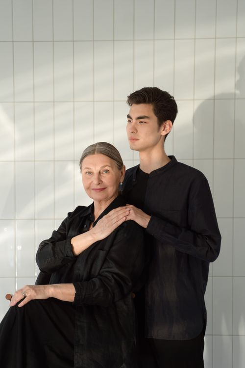 Free A senior woman with a young man posing against a tiled wall in a well-lit area. Stock Photo