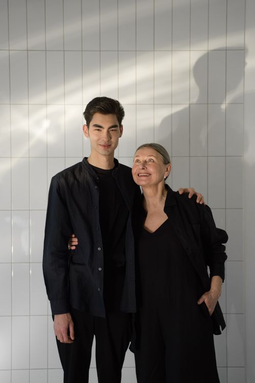 Free Mother and son in black outfits smiling warmly indoors against a tiled wall. Stock Photo