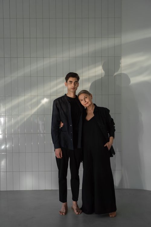 Free A mother and son in black clothes stand closely together indoors, showcasing family love and style. Stock Photo