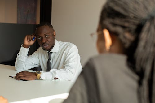 L'homme En Chemise Blanche Assis à Côté De La Table