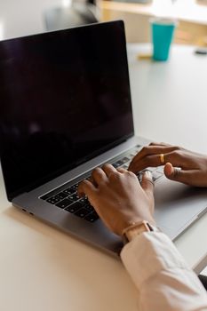 A person typing on a laptop in a modern indoor workspace, focusing on productivity.
