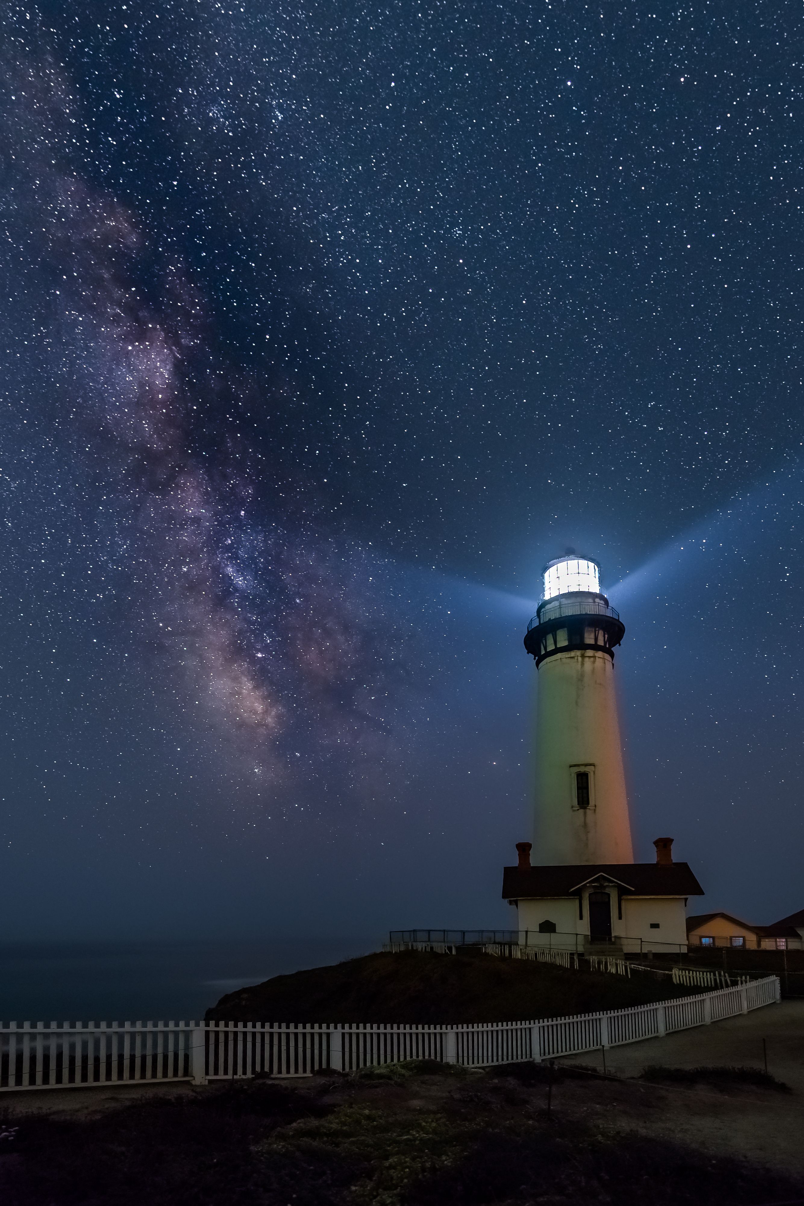 Lighthouse glowing on starry sky · Free Stock Photo