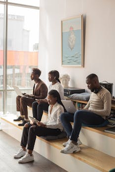 Group of four diverse professionals working with devices in a modern office space.