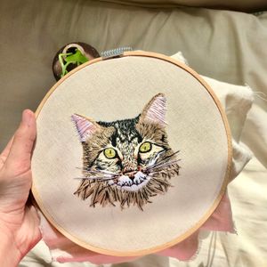 Hand-embroidered cat portrait in a wooden hoop, photo by Marina Meyer on Pexels