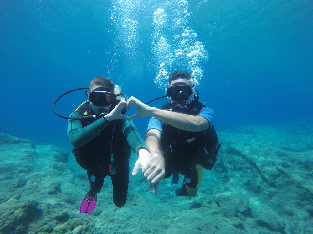 A Sweet Couple Swimming Underwater while Holding Each Others Hand