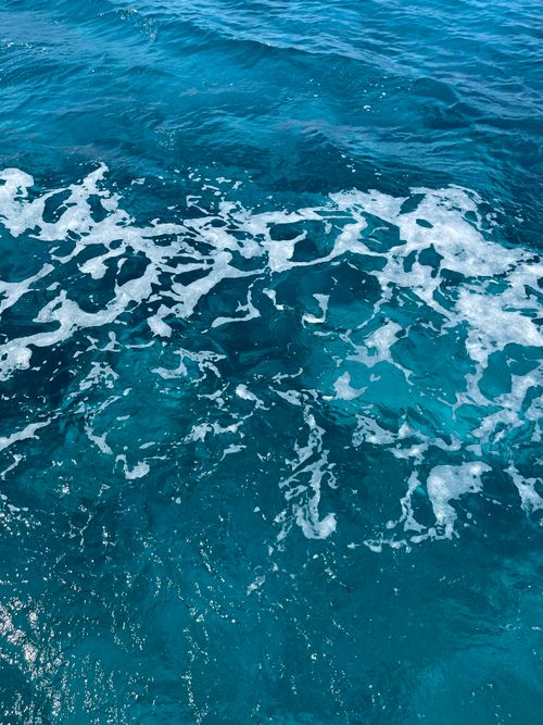 Free Close-up of vibrant blue ocean waves with foamy ripples creating a dynamic texture. Stock Photo