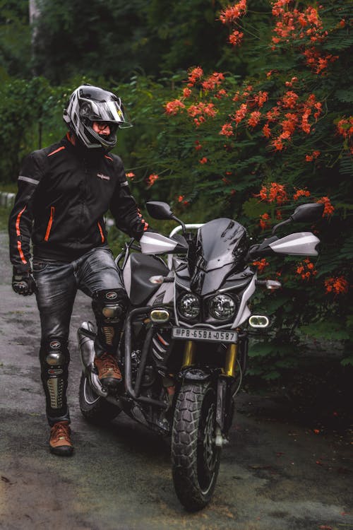 Man in Black Jacket Standing Beside a Black Motorcycle