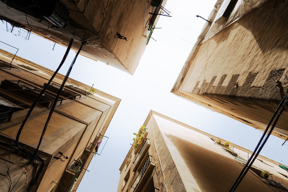 Vista en ángulo bajo de edificios históricos en el Barrio Gótico de Barcelona bajo un cielo despejado.