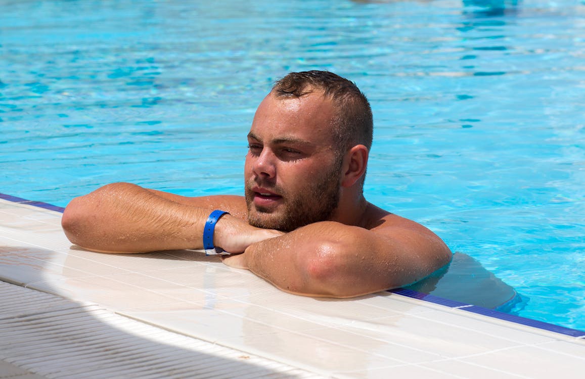 pexels photo 9481118 Free Man in Blue Shorts Lying on White Surfboard on Blue Water Stock Photo