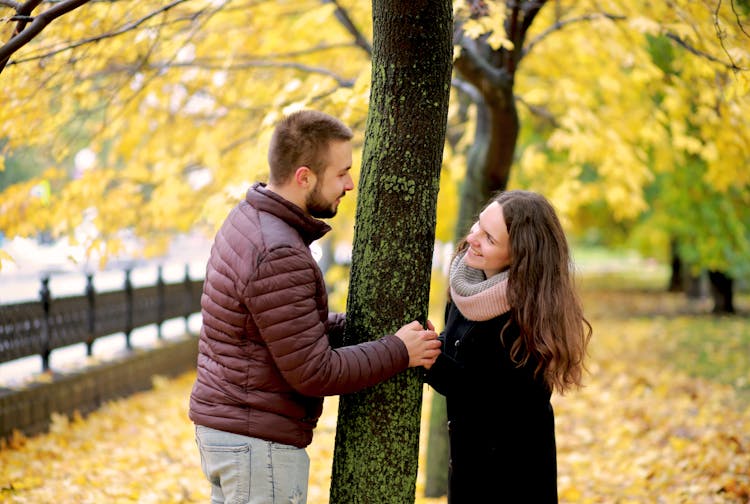Smiling Couple Standing By The Tree 
