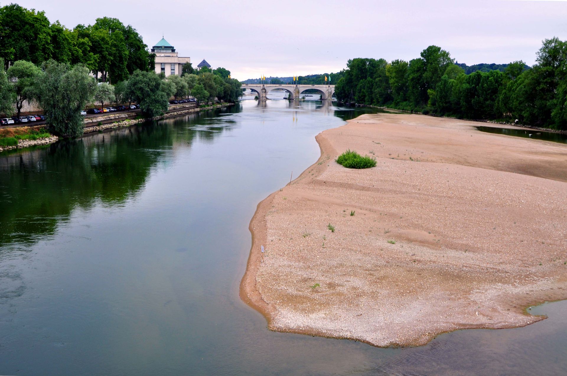 Picturesque view of the Loire River with a historic bridge and lush greenery in Tours, France.