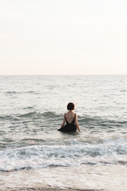 A Woman in Black Dress Standing on the Sea