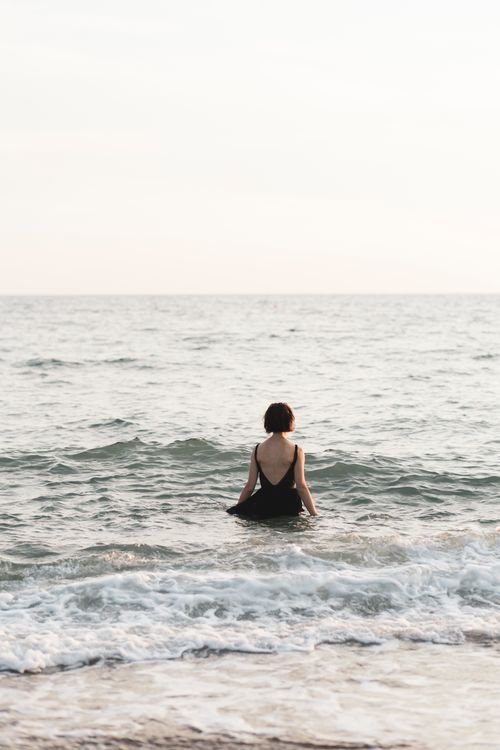 Free Woman standing in the sea, capturing a serene and introspective moment. Stock Photo