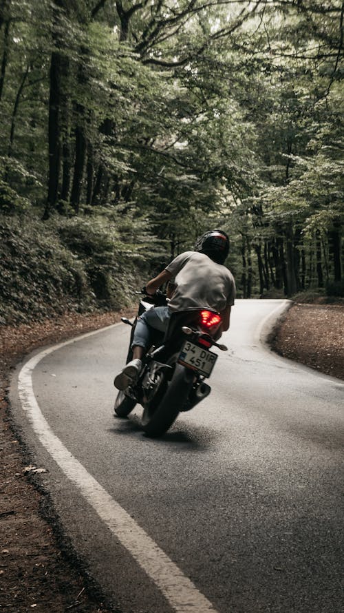 Man Wearing Helmet Riding Motorcycle on Road