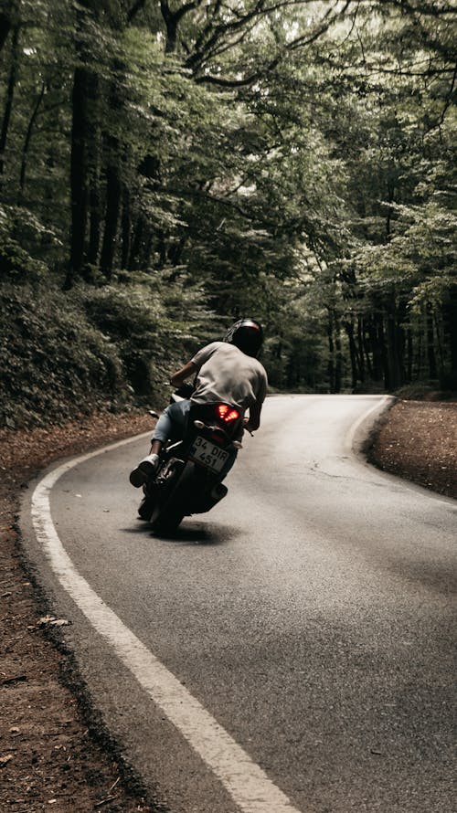Photograph of a Man Riding a Motorcycle on a Road