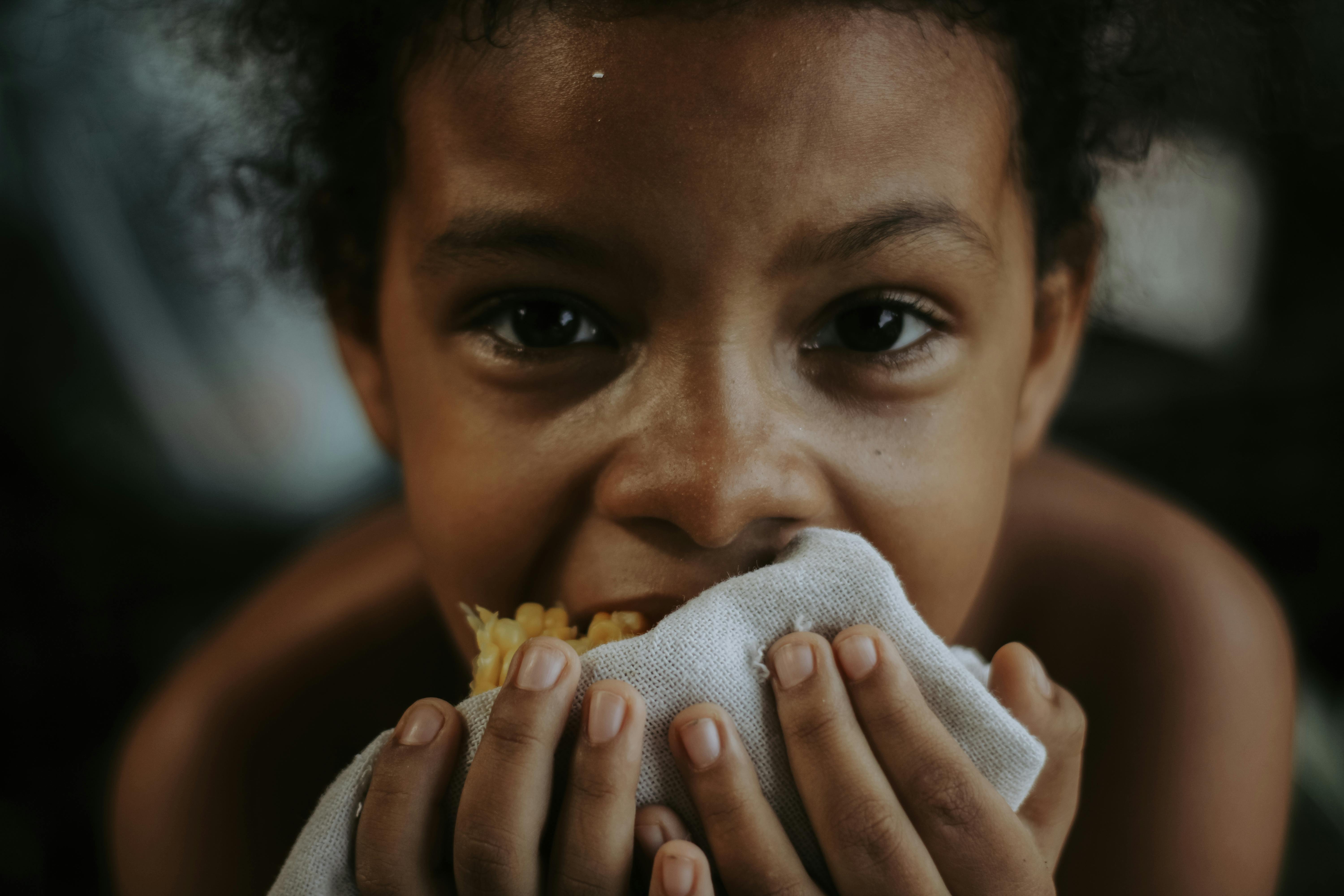 Adorable child eating corn close-up, captures innocence and joy.
