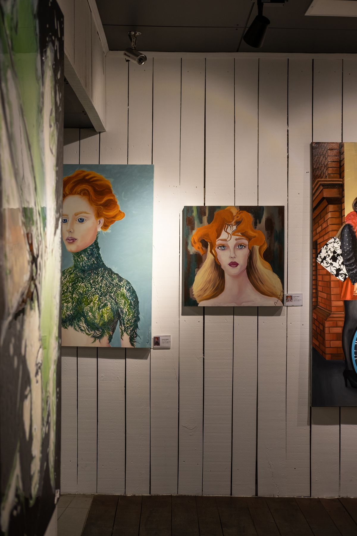 A gallery wall hung with colourful portrait paintings