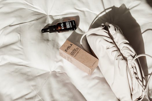 Top view of Evela brand skincare products with handbag on a white textile background.