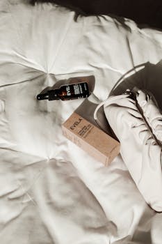 Flat lay of rose hip oil bottle and packaging on white fabric, with bag. Ideal for beauty concepts.