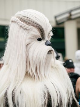 Chewbacca cosplay character with white furry costume at an outdoor street event.