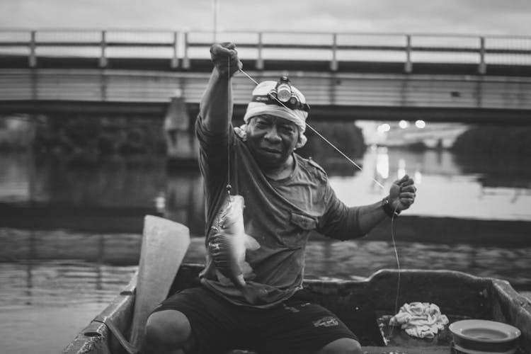 Grayscale Photo Of A Man Catching Fish