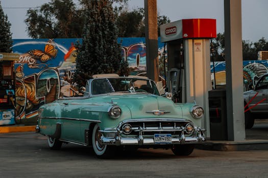A classic vintage car parked at a gas station with colorful graffiti in Colorado Springs.