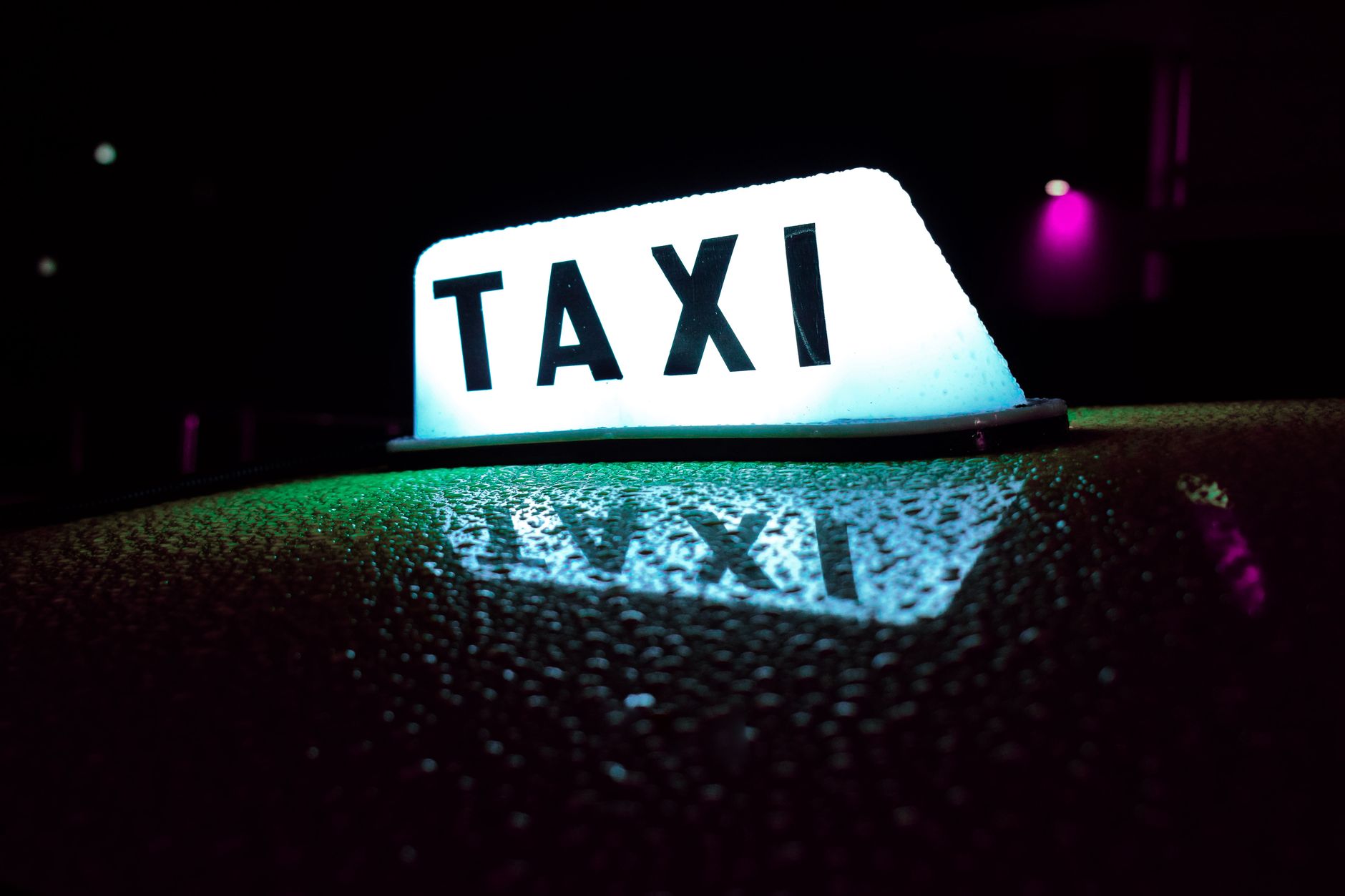 Close-up of a glowing taxi sign reflecting on a wet surface in Panama's nighttime ambiance.